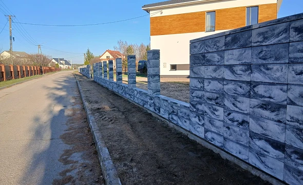 Ogrodzenia z bloczków betonowych o marmurowym wzorze z murowanymi słupkami przy nowoczesnym domu